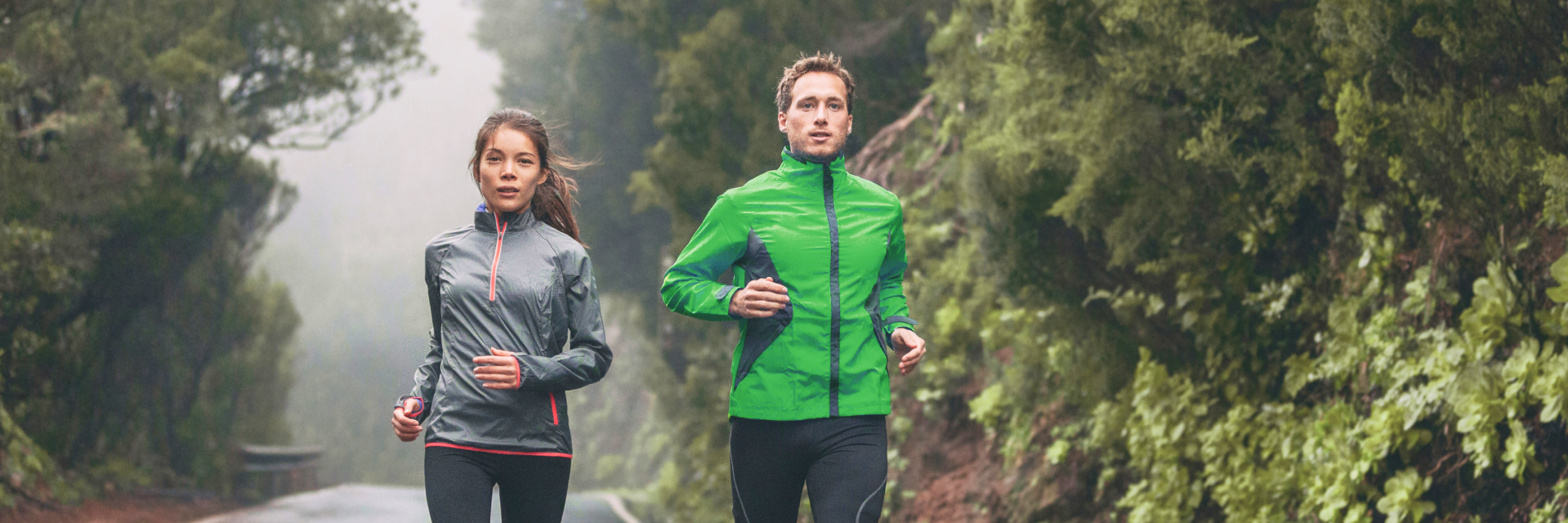 A photo of two people running in the woods.