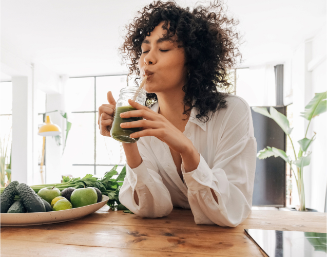 A photo of a woman drinking green beverage.