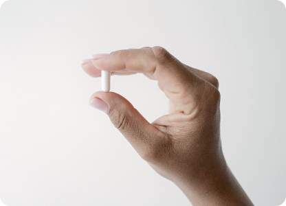 A photo of a hand holding capsule.